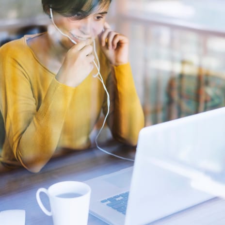 Woman taking a private English class online using a laptop and headset at home