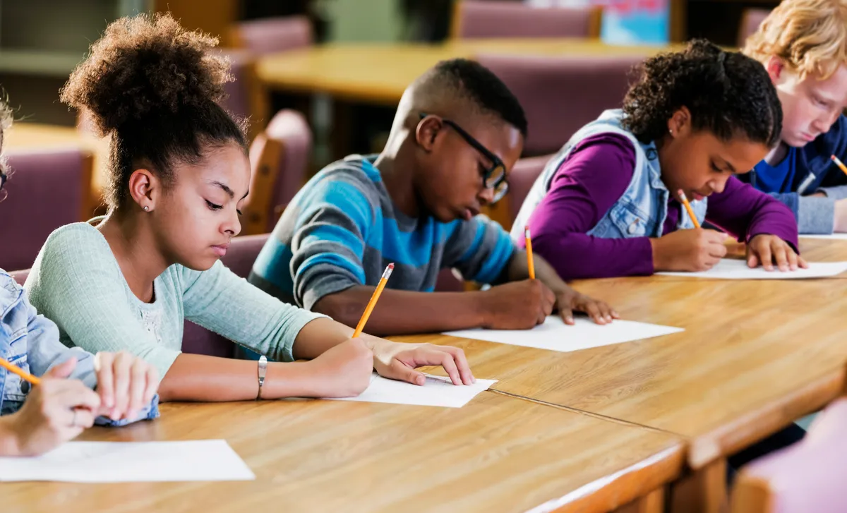 A diverse group of elementary school children focused on writing during a classroom language learning program