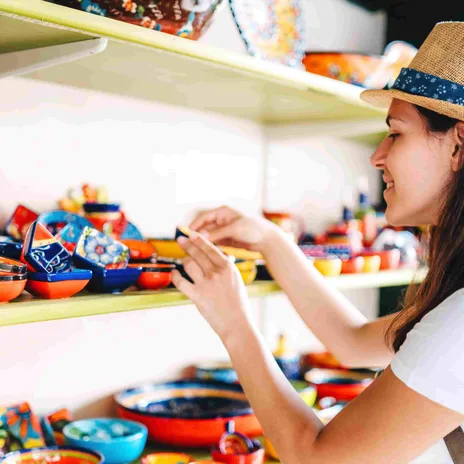Smiling woman browsing colorful handmade ceramics, capturing the cultural immersion aspect of Berlitz Spanish courses.