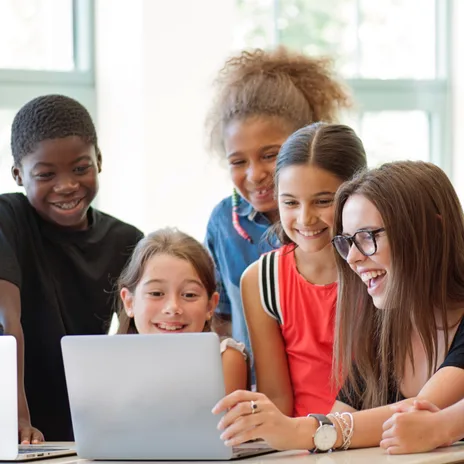 Group of diverse school children smiling and learning on laptops during a language class