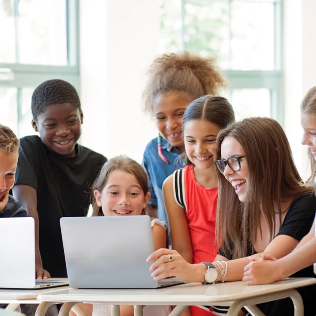 Group of diverse school children smiling and learning on laptops during a language class