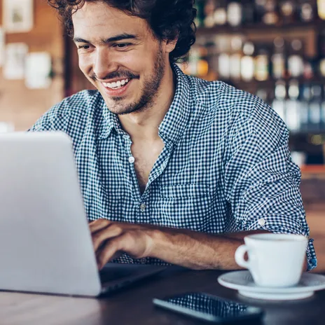 Man smiling while attending online Portuguese group class from a café