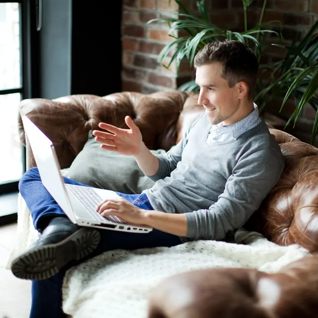 Smiling man learning from home on a video call, representing flexibility and comfort with Berlitz online language schools.

