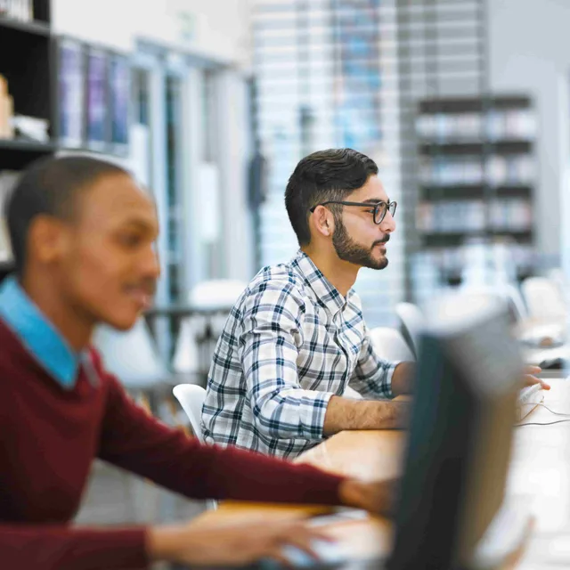 Students working on desktop computers in a modern library.