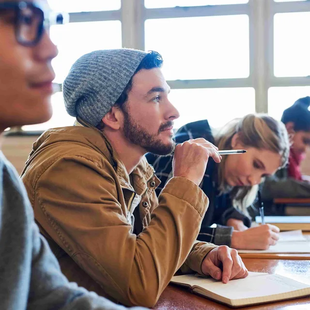 Students focused in class, listening and taking notes.