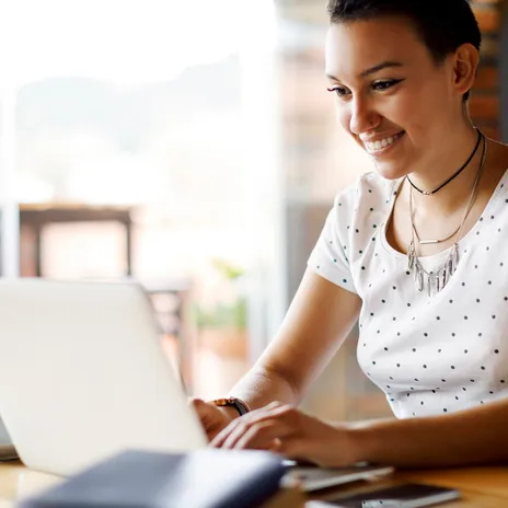 Smiling young professional working remotely on a laptop, representing the flexible and global opportunities available through Berlitz careers.

