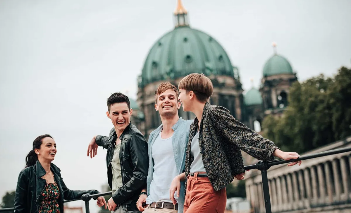 Group of young adults smiling and chatting outside a historic building in Berlin, symbolizing the cultural immersion offered by Berlitz language school programs.