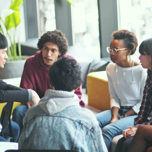 A diverse group of students in a lively discussion setting, representing collaborative learning environments available through online German classes.